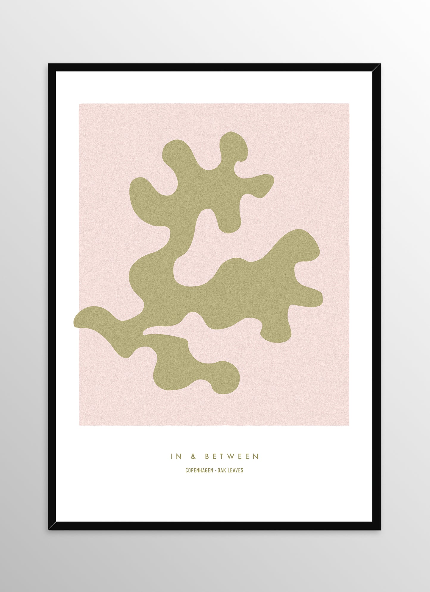 Art print of gold oak leaf on soft pink background in black wooden frame.