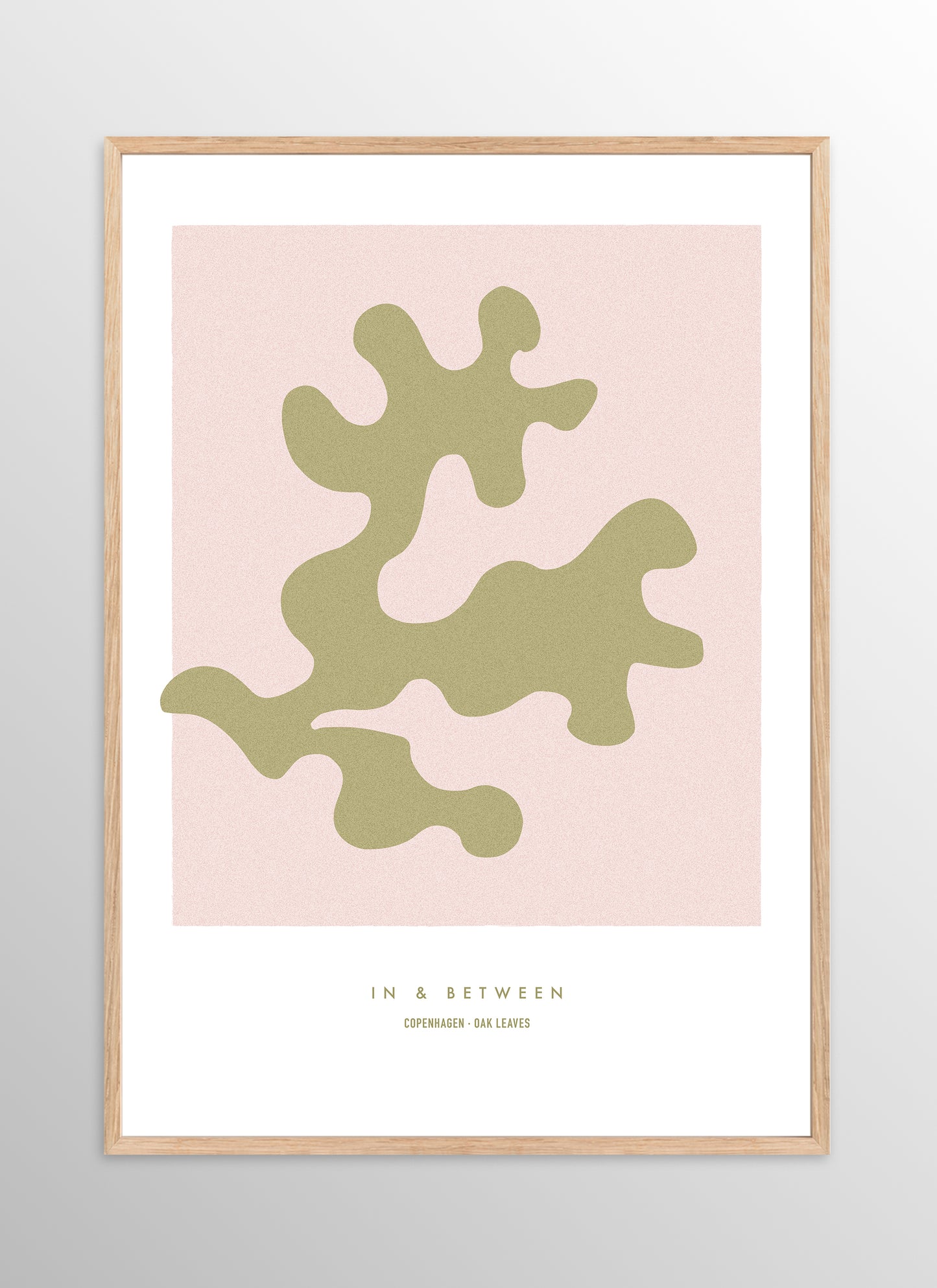 Art print of gold oak leaf on soft pink background in natural wooden frame.