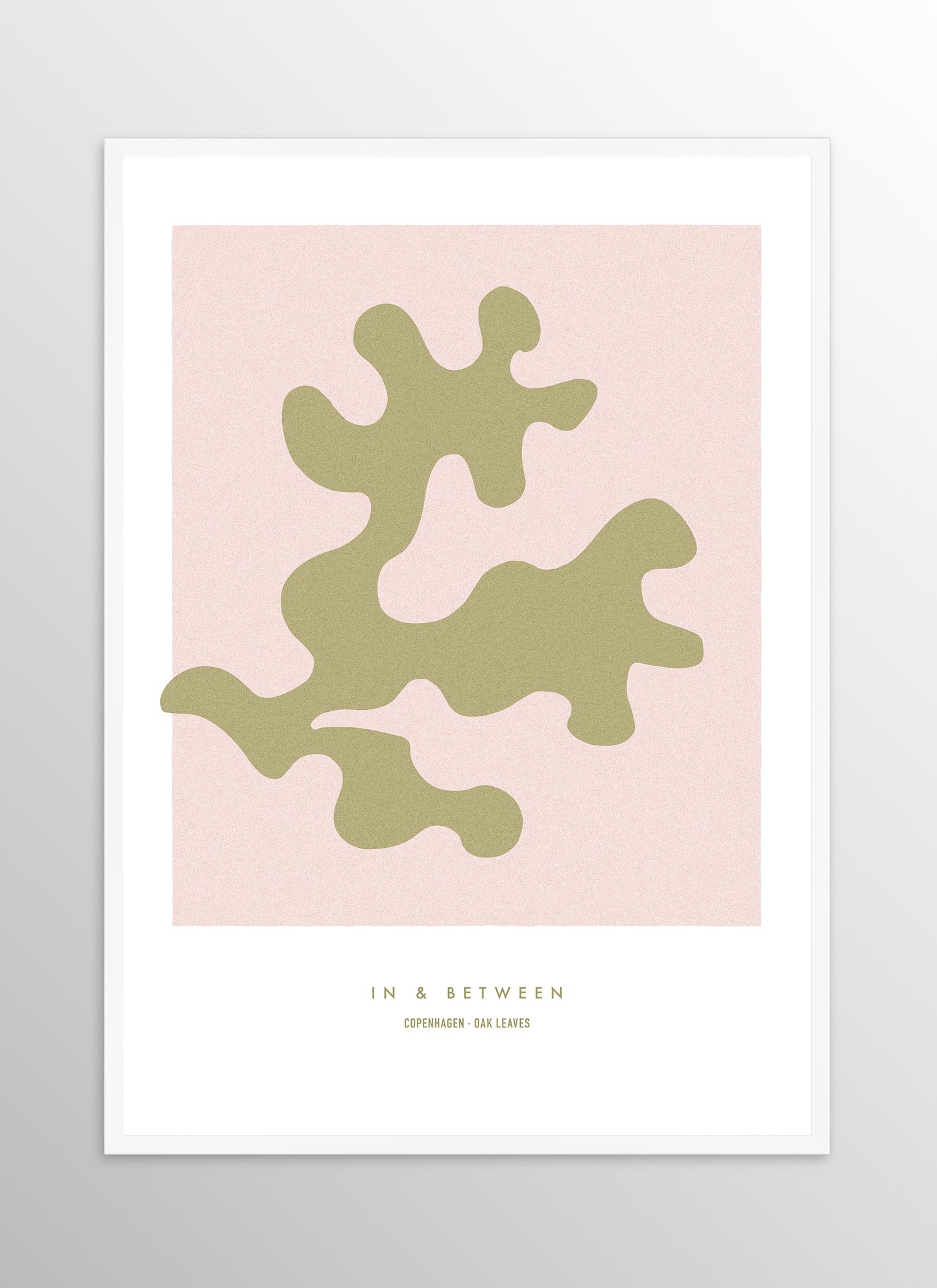Art print of gold oak leaf on soft pink background in white wooden frame.