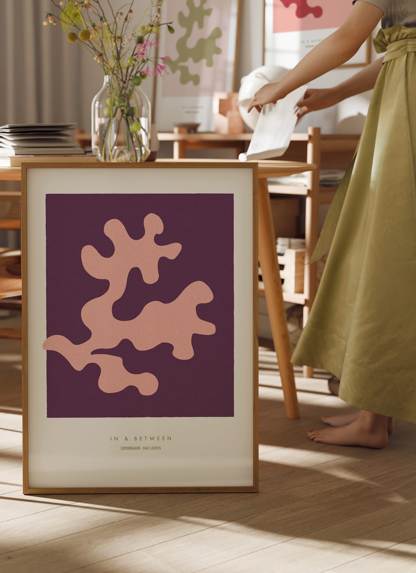 Lifestyle image with In and Between art print of peach oak leaf on dark violet background in natural wooden frame.