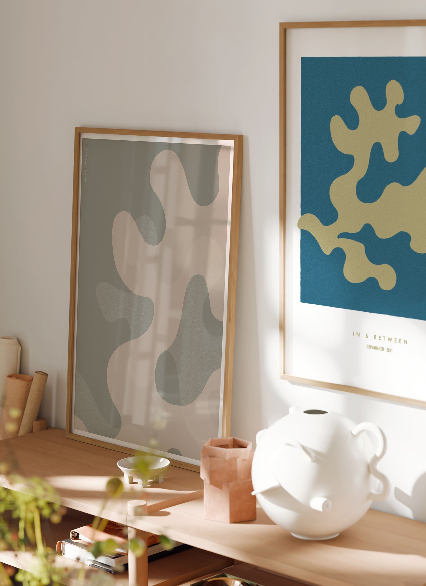 Lifestyle image of In and Between art print of golden oak leaf on dark blue background in natural wooden frame.