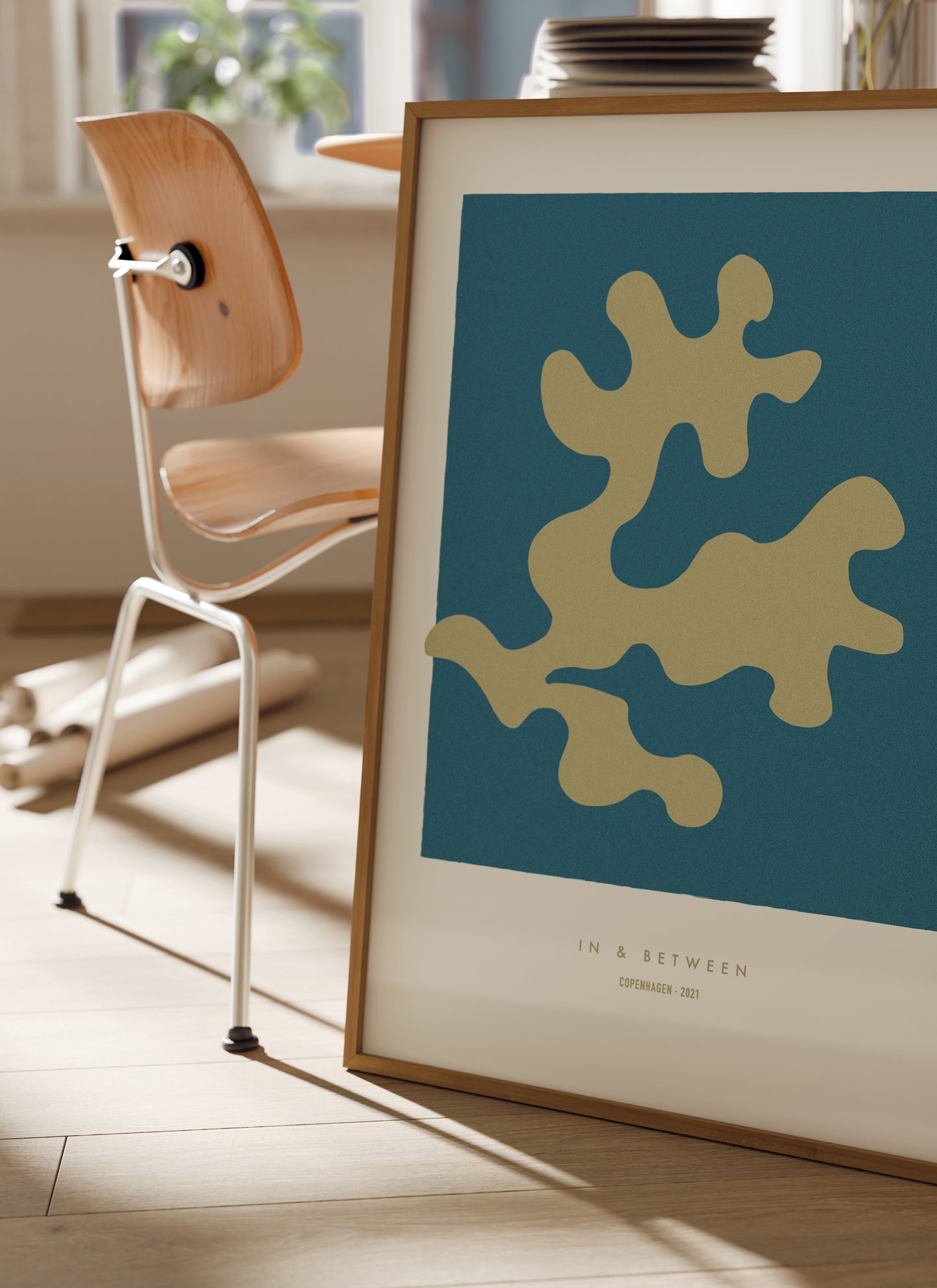 Lifestyle image of In and Between art print of golden oak leaf on dark blue background in natural wooden frame.