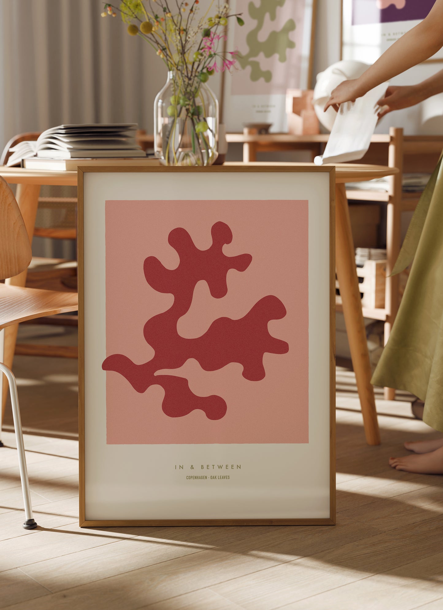 Art print of strawberry ice red oak leaf and background in natural wooden frame standing on floor in a room setting.
