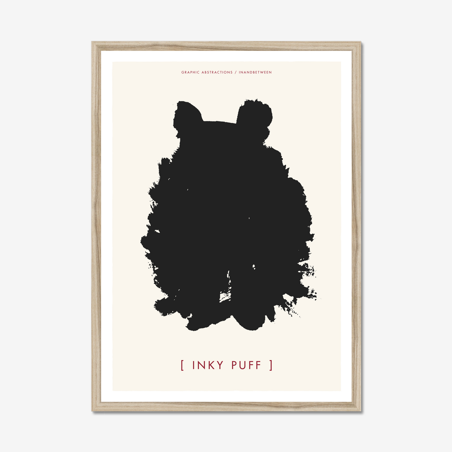 Art print in natural wood frame showing ink black fluffy creature with ears on a cream background.