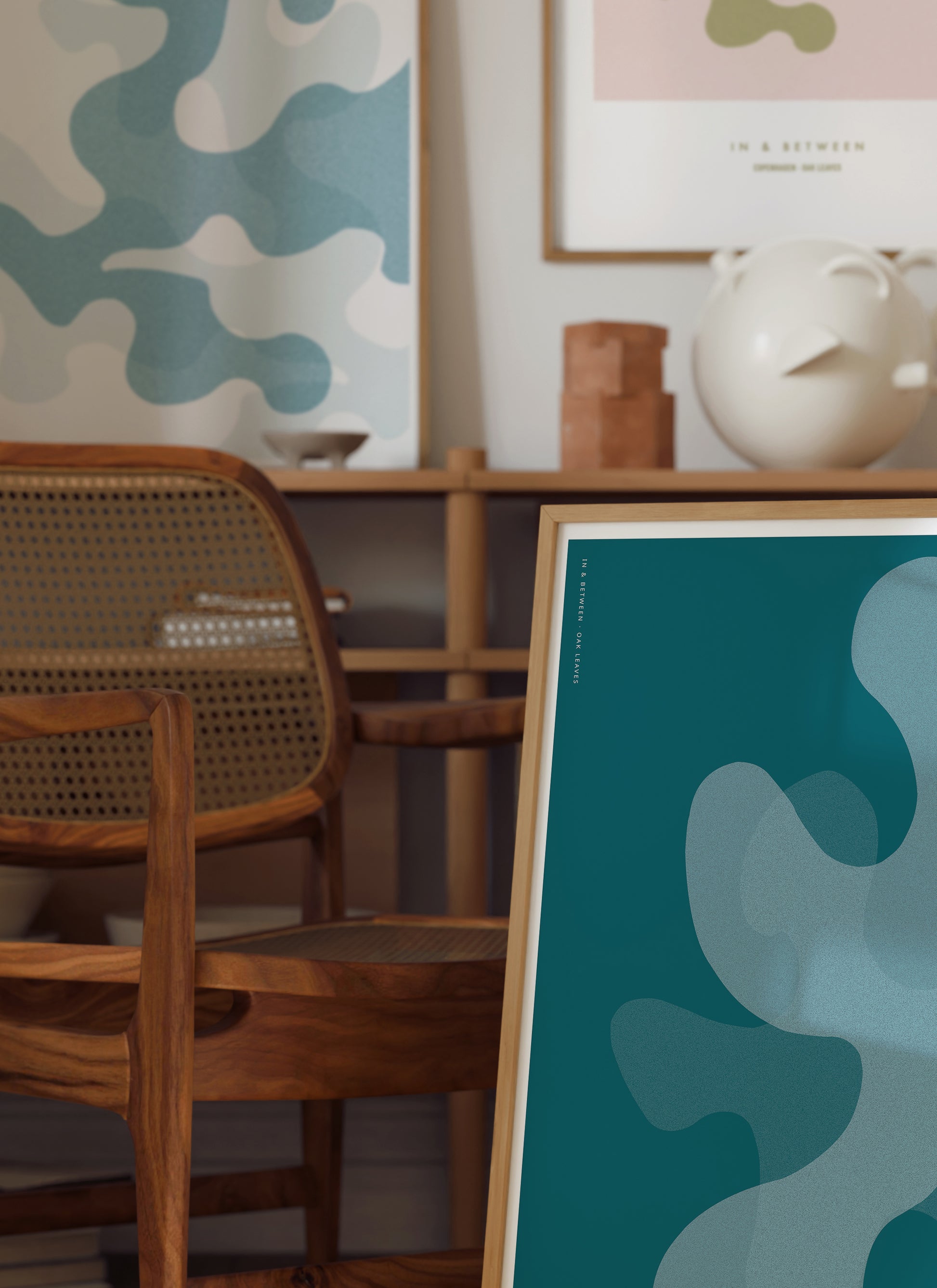 Lifestyle image of In and Between art print of large deep ocean blue oak leaf shapes in natural wooden frame.