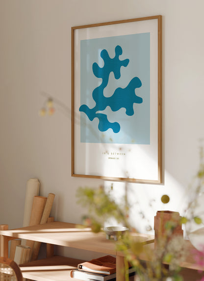 Lifestyle image with art print oak leaf and background in light blue in natural wooden frame.