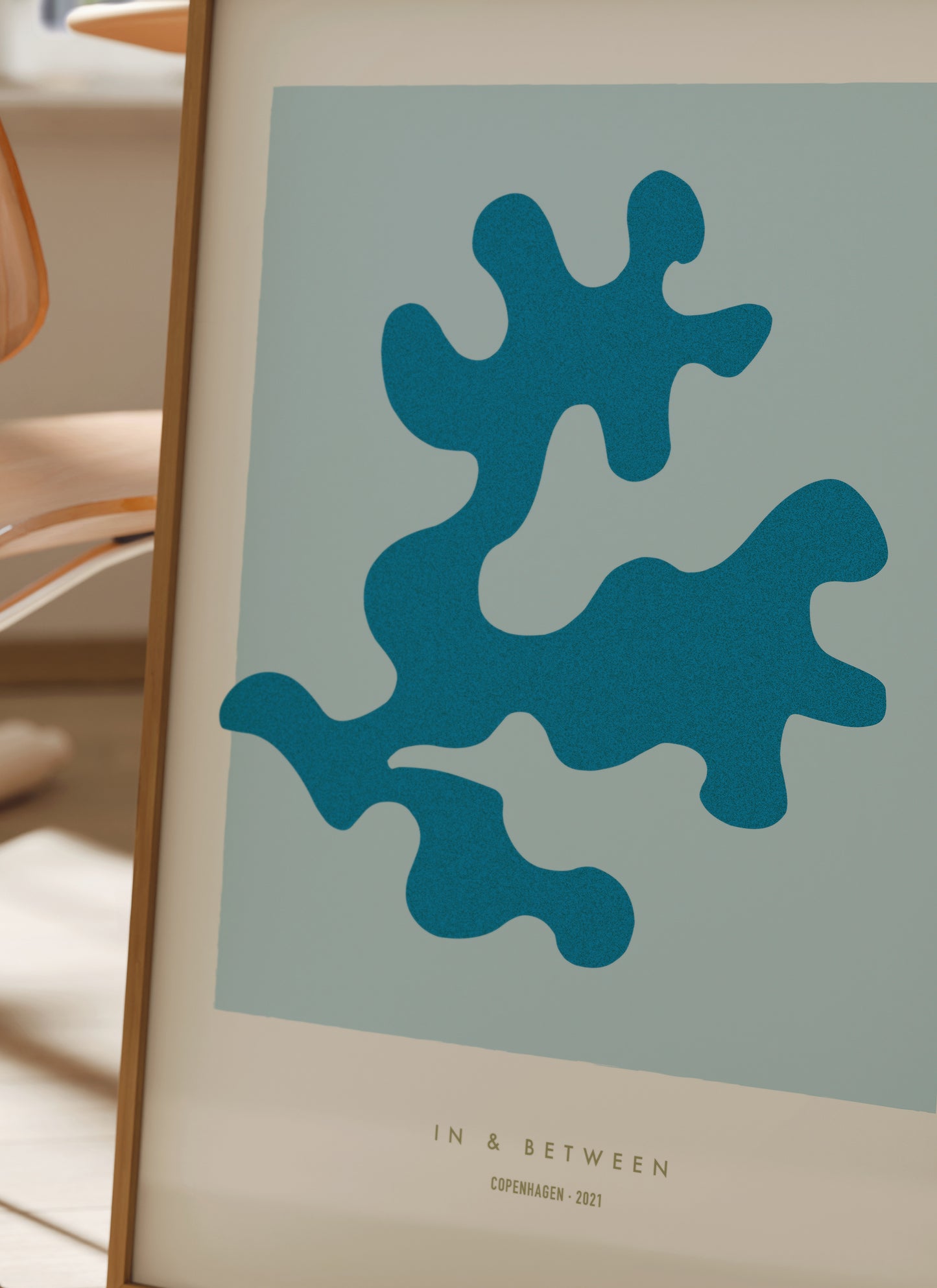 Lifestyle image with art print oak leaf and background in light blue in natural wooden frame.