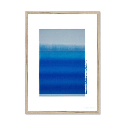 Natural wood framed giclee print depicting a vibrant blue horizon within a wide white border. From being completely saturated at the bottom the pigments of colour slowly spread out upwards until it fades into space at the top like the horizon.